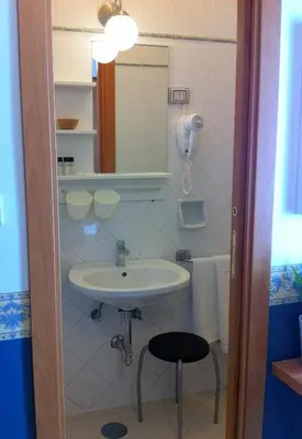 a bathroom with a sink and a mirror and a stool at Hotel Carmel in Rome