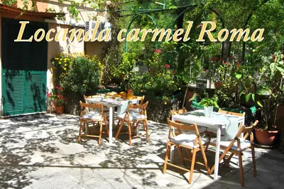 a restaurant with tables and chairs in a garden at Hotel Carmel in Rome
