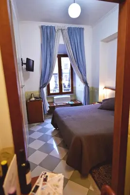 a bedroom with a bed and a window with blue curtains at Hotel Carmel in Rome