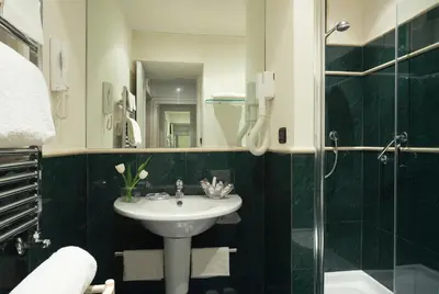 a bathroom with a sink and a mirror and a shower at Hotel Gregoriana in Rome