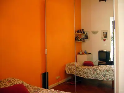 an orange room with two beds and a mirror at B&B&Courtesy in Rome