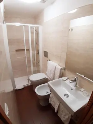 a white bathroom with a toilet and a sink at Hotel Mariano in Rome