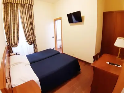 a bedroom with a blue and white bed and a window at Hotel Mariano in Rome