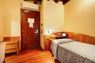 a bedroom with a bed and a desk and a door at Hotel Corot in Rome