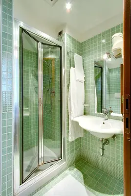 a green tiled bathroom with a sink and a shower at Hotel Corot in Rome