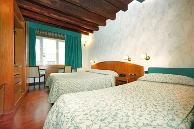 a hotel room with two beds and a table at Hotel Corot in Rome