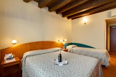 a bedroom with two beds with a bottle of wine on a table at Hotel Corot in Rome