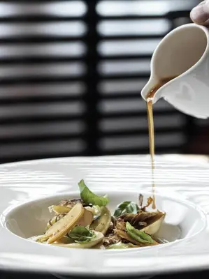 a plate of food with a spoon pouring peanut sauce on it at J.K. Place Roma - The Leading Hotels of the World in Rome
