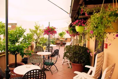 a patio with tables and chairs and potted plants at Hotel Novecento in Rome