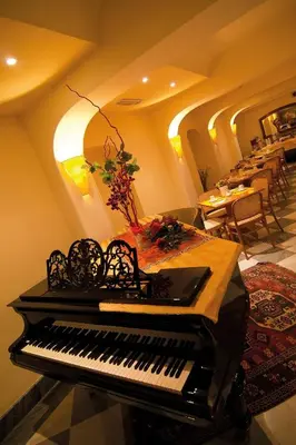 a piano in a room with a table and chairs at Hotel Novecento in Rome