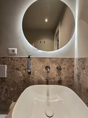 a bathroom sink with a round mirror above it at Hotel Porta Pia in Rome