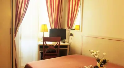 a hotel room with a bed and a desk and a window at Hotel Villa Rosa in Rome