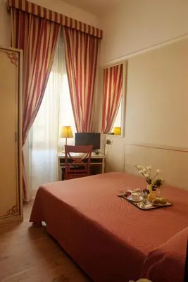 a hotel room with a bed with a table and a desk at Hotel Villa Rosa in Rome