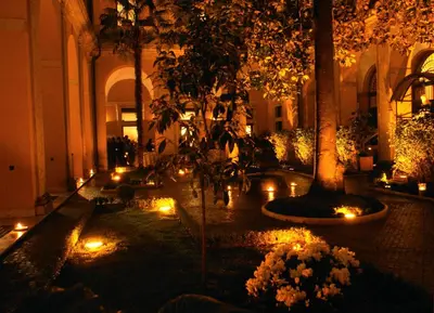 a courtyard with candles and trees in a building with lights at Palazzo Cardinal Cesi in Rome