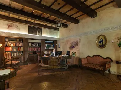 a man sitting at a desk in a library with a laptop at Palazzo Cardinal Cesi in Rome