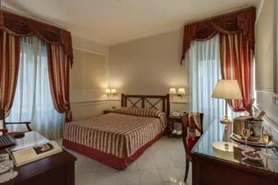 a hotel room with a bed and a desk at Palazzo Cardinal Cesi in Rome