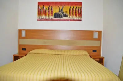 a bedroom with a yellow bed with a painting above it at Hotel Moscatello in Rome