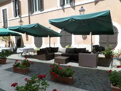 a patio with couches and umbrellas and flowers at Relais Hotel Antico Palazzo Rospigliosi in Rome