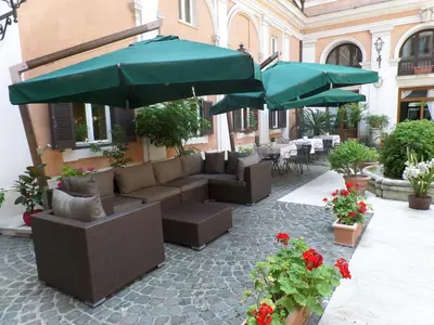 a patio with couches and umbrellas and flowers at Relais Hotel Antico Palazzo Rospigliosi in Rome