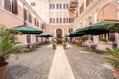 an empty street with tables and chairs and umbrellas at Relais Hotel Antico Palazzo Rospigliosi in Rome