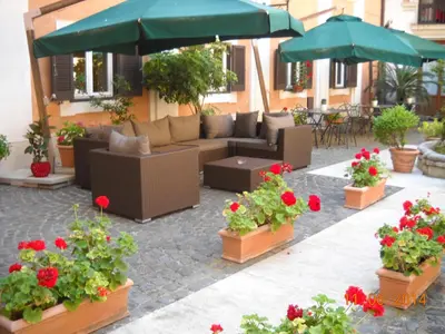 a patio with a couch and some flowers and umbrellas at Relais Hotel Antico Palazzo Rospigliosi in Rome