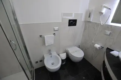 a white bathroom with a toilet and a sink at Notti A Roma in Rome