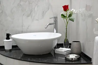 a bathroom with a white sink and a vase with a rose at Notti A Roma in Rome