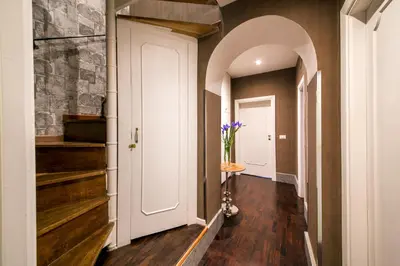 an arched hallway with a white door and stairs at The Inn at the Roman Forum Luxury Collection - The Inn At The Roman Forum in Rome