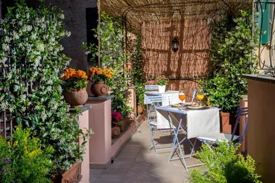 a patio with tables and chairs and plants at The Inn at the Roman Forum Luxury Collection - The Inn At The Roman Forum in Rome