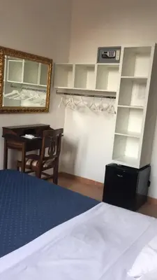 a bedroom with a bed and a desk and a mirror at Hotel Caracciolo in Rome