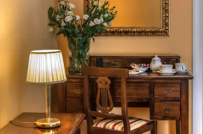 a table with a vase of flowers and a lamp at Hotel Caracciolo in Rome