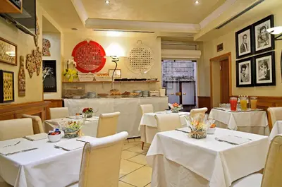 a restaurant with white tables and chairs and a counter at Hotel Homs in Rome