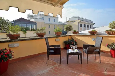 a patio with chairs and a table on a balcony at Hotel Homs in Rome
