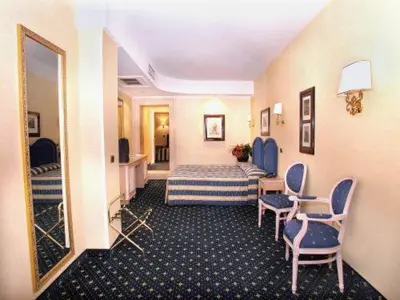 a hotel room with a bed and chairs and a mirror at Hotel Valle in Rome