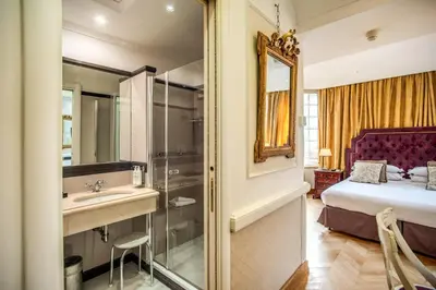 a bedroom with a bed and a sink and a mirror at The Britannia Hotel in Rome