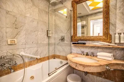 a bathroom with a tub and a sink and a mirror at The Britannia Hotel in Rome