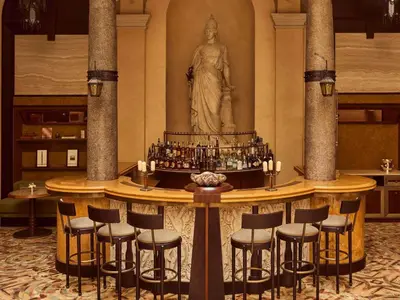 a bar with stools and a statue of a woman at Orient Express La Minerva in Rome