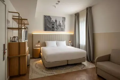 a bedroom with a bed and a chair and a couch at Cosmopolita Rome Colosseum, Tapestry Collection by Hilton in Rome
