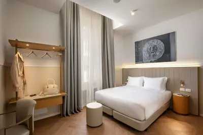 a hotel room with a white bed and a desk at Cosmopolita Rome Colosseum, Tapestry Collection by Hilton in Rome