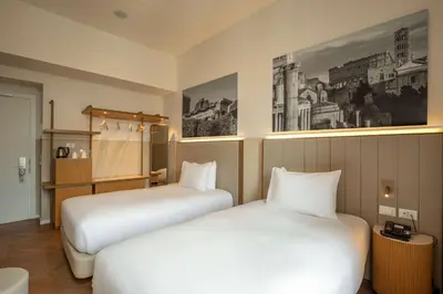 two beds in a hotel room with white sheets at Cosmopolita Rome Colosseum, Tapestry Collection by Hilton in Rome