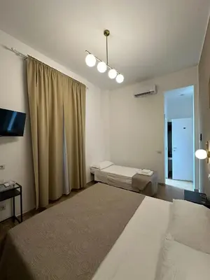 a bedroom with two beds and a tv and a window at Hotel Lodi in Rome