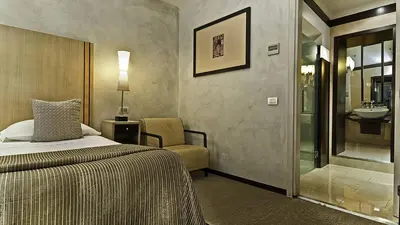 a bedroom with a bed and a chair and a sink at Intown Luxury House in Rome