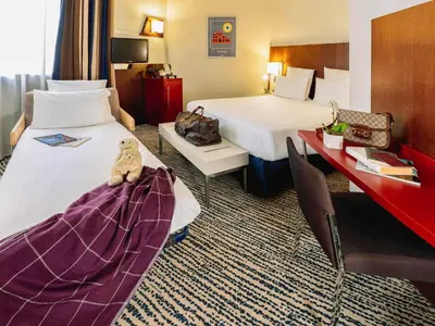 a bedroom with a large white bed and a red curtain at Mercure Roma Piazza Bologna in Rome