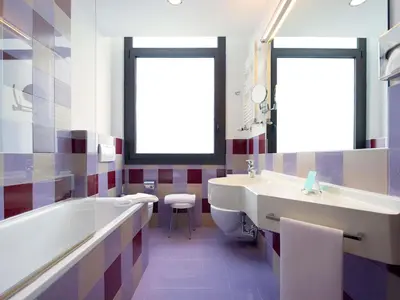 a bathroom with two sinks and a toilet and a window at Mercure Roma Piazza Bologna in Rome