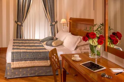 a bedroom with a bed and a table with roses at Albergo Ottocento in Rome