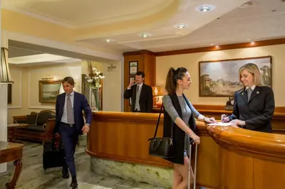 a man and a woman standing at a reception desk at Albergo Ottocento in Rome