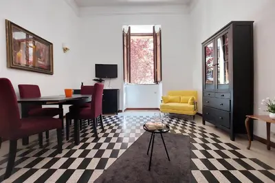 a living room with a table and a yellow chair at 4BNB - Quiriti Delightful Apartment in Rome