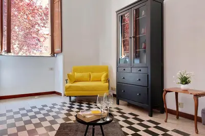 a living room with a yellow chair and a dresser at 4BNB - Quiriti Delightful Apartment in Rome