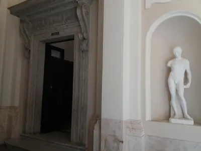 a statue of a man sitting on a ledge next to a door at Residence Europa in Rome