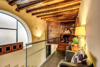 a woman sitting at a desk in a room with wooden ceilings at Trevi Beau Boutique Hotel in Rome